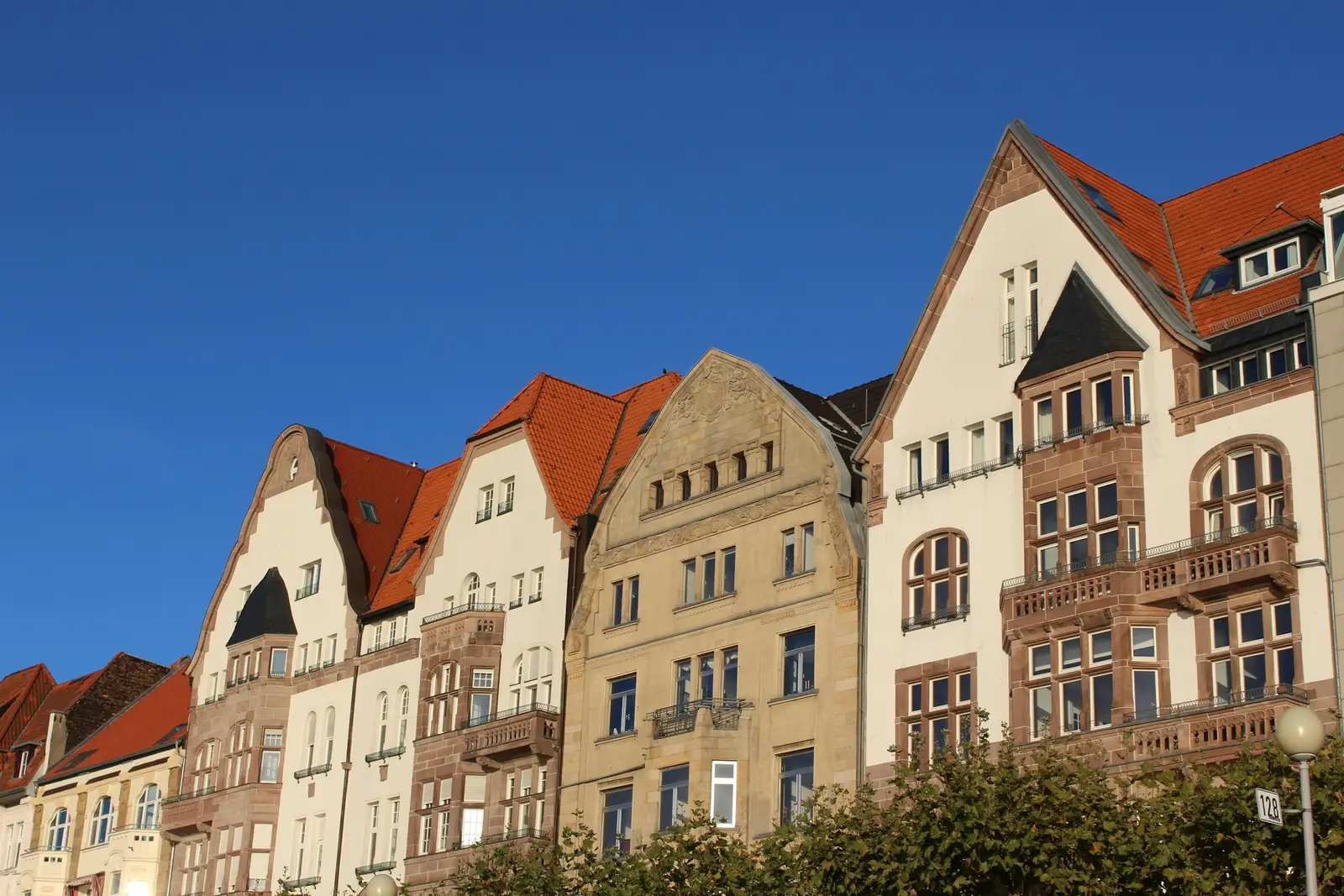 Reihe alter Stadthäuser mit Giebeln und Erkern unter blauem Himmel