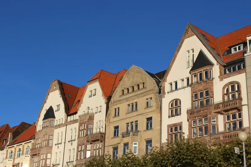 Reihe alter Stadthäuser mit Giebeln und Erkern unter blauem Himmel