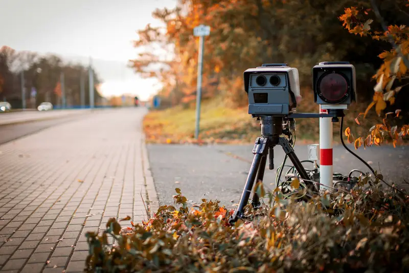 Mobiles Blitzgerät auf einem Stativ am Rand einer Landstraße im Herbst