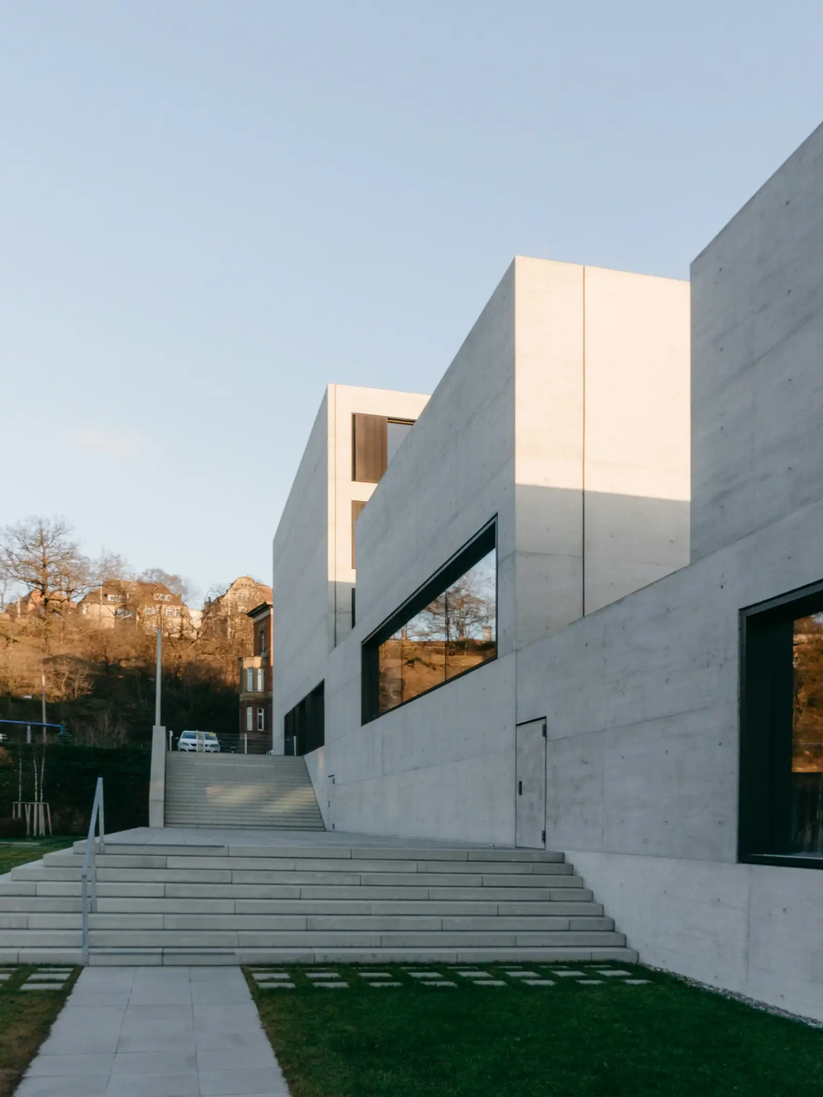 Wohnhaus aus hellen, gegeneinander versetzten Betonkuben mit breiter Außentreppe