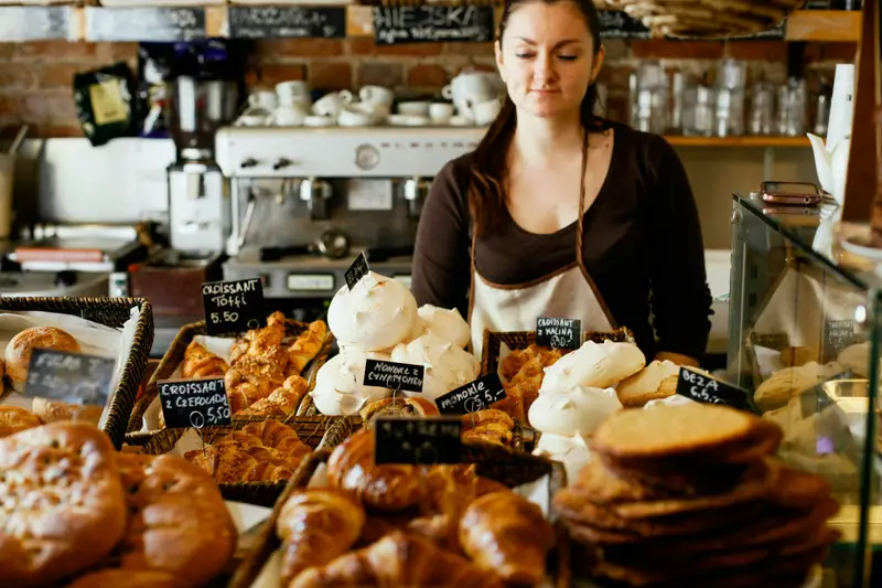 Frau hinter der Theke eines Cafés mit Backwaren