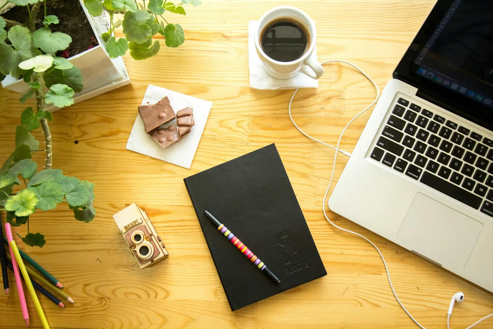 Notizbuch, Laptop und Kaffee auf einem hellen Holztisch
