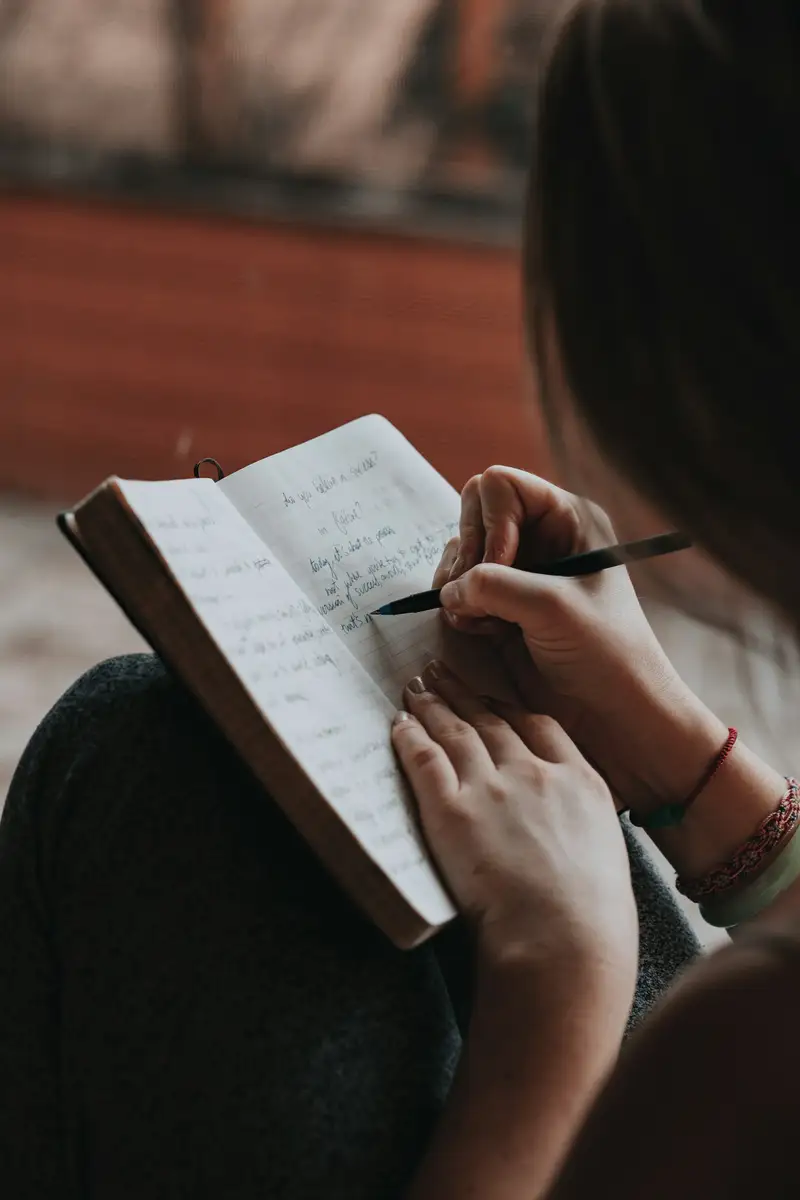 Frau schreibt Gedanken in ein Notizbuch