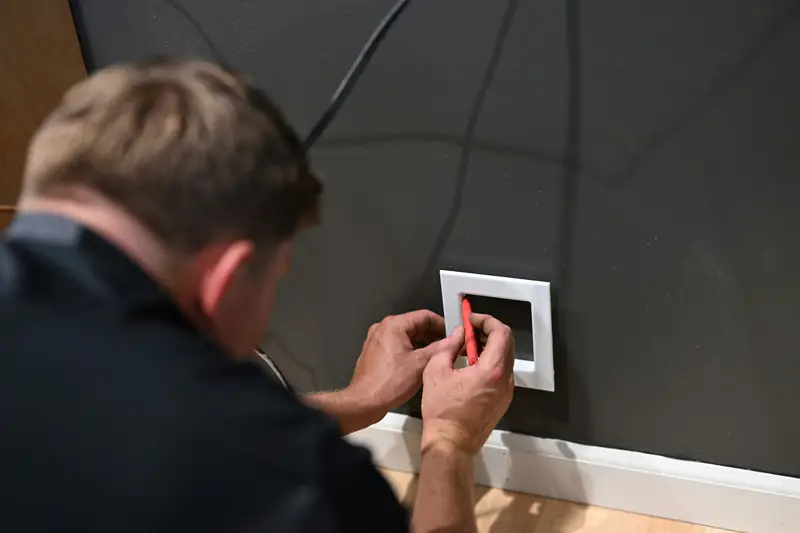 Elektriker setzt einen Lichtschalter in die Wand