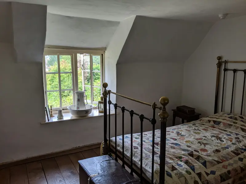 Dachzimmer mit Metallbett und Sprossenfenster