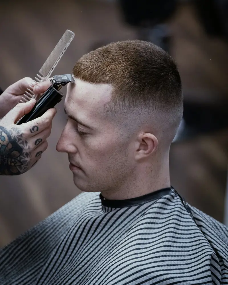 Herrenschnitt mit kurzem Fade, Friseur arbeitet mit Kamm und Maschine