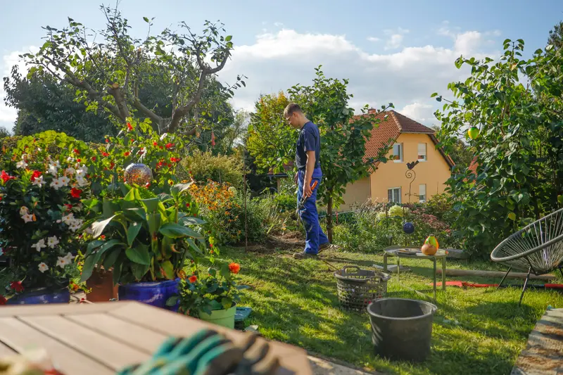 Gärtner bei der Arbeit in einem Hausgarten mit Staudenbeeten