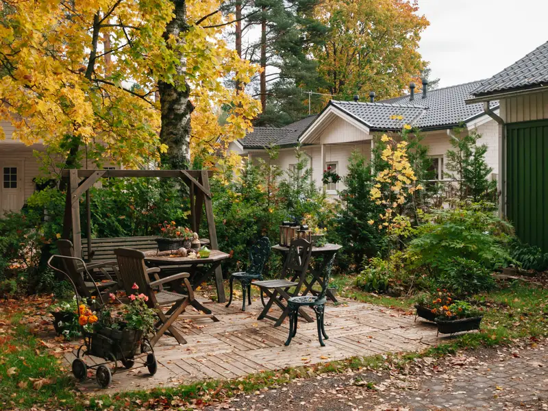 Gepflasterter Sitzplatz mit Bank und Tisch in einem herbstlichen Hausgarten