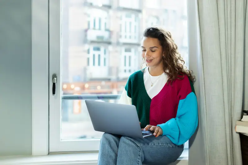 Selbstständige mit Laptop am Altbaufenster