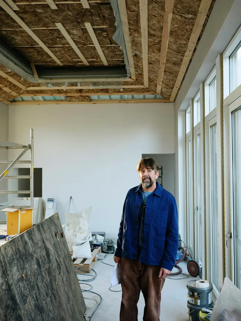 Sven Kiefer in blauer Arbeitsjacke auf einer Innenbaustelle