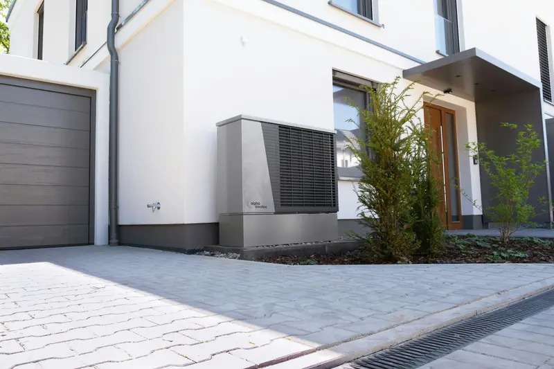 Wärmepumpe an der Fassade eines Einfamilienhauses mit Garage
