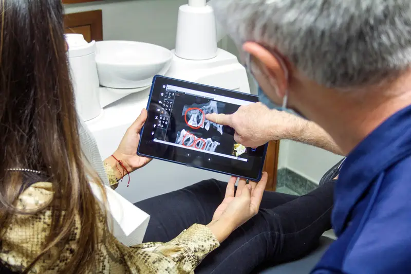 Zahnarzt erklärt einer Patientin ein Röntgenbild auf dem Tablet